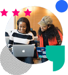 Two women sitting with laptops and working together